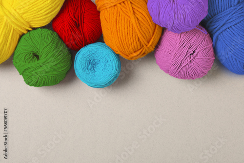 Balls of yarn in rainbow colors on light background, flat lay. Space for text