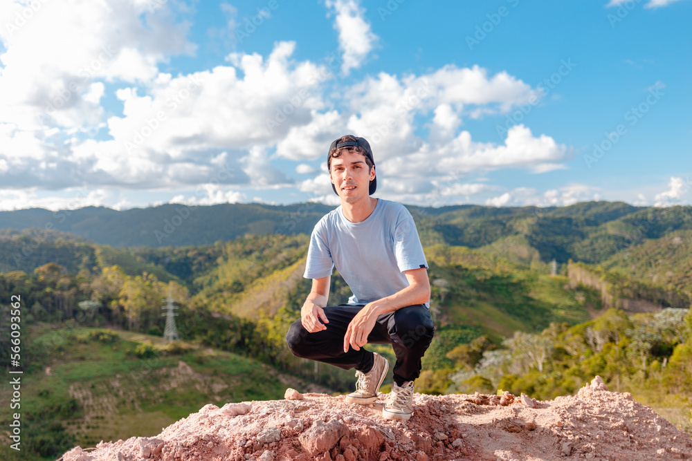Outdoor portrait of young Brazilian man looking at camera with mountains landscape in background. Posing for a photo after hiking the trail. Outdoor portrait of young Brazilian man looking at camera with mountains landscape in background. Posing for a photo after hiking the trail.