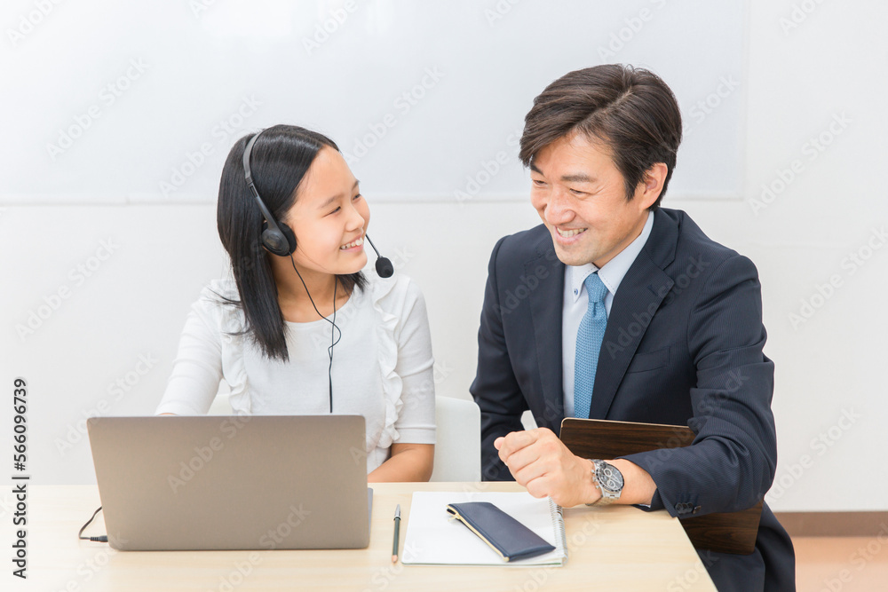 学校の授業・塾でで英会話のリスニング・ヒアリングレッスンをする先生・教師と子供（女の子・日本人）