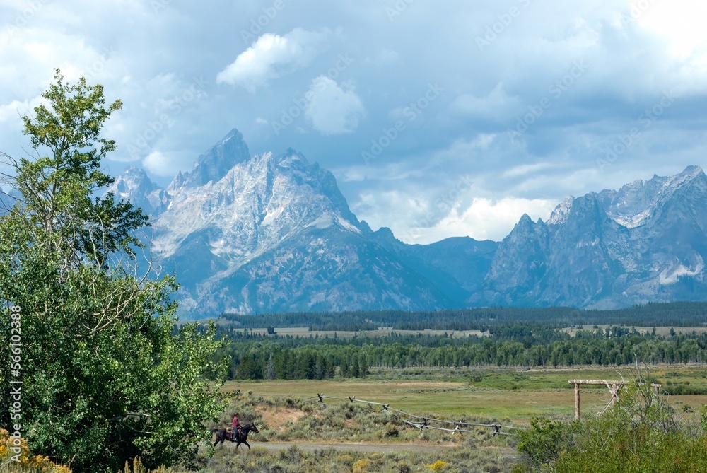 A lone cowboy on a horse under the spectacular Tetons in Wyoming