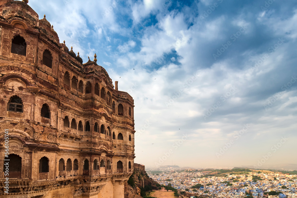 View of Mehrangarh fort with distant view of blue city Jodhpur, Rajasthan, India. Historical Fort is UNESCO world heritage site. Blue sky with white clouds in the background.