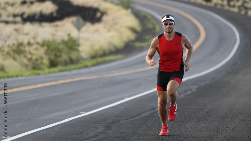 Triathlete running in triathlon suit training for ironman. Male runner exercising running uphill on road Kailua-Kona, Big Island, Hawaii. SLOW MOTION Triathlete running in triathlon suit training for ironman. Male runner exercising running uphill on road Kailua-Kona, Big Island, Hawaii. SLOW MOTION