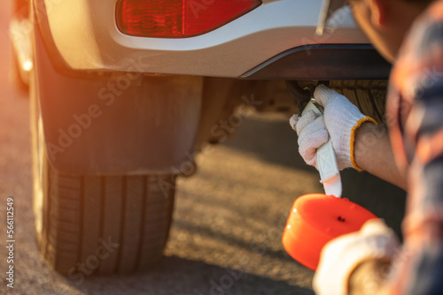 Tableau sur toile Man holding emergency car towing line and hook on backside of car on the roadside