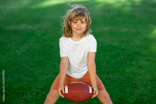 Sport kid. Young boy playing american football. Child holding rugby ball while playing american football in Summer park.
