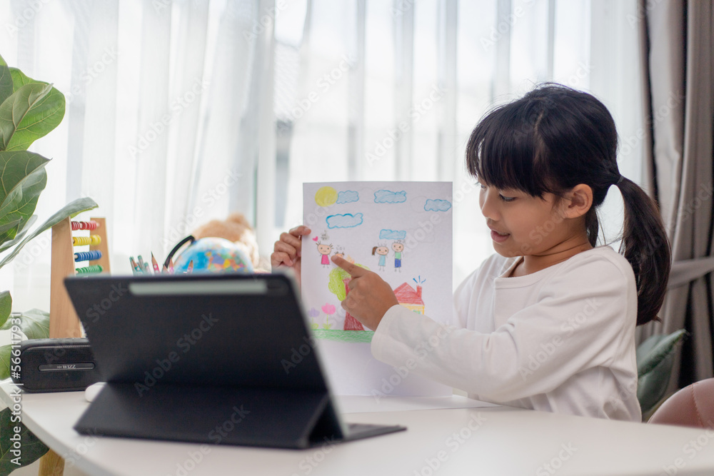 Asian schoolgirl doing her homework with digital tablet at home. Children use gadgets to study. Education and distance learning for kids. Homeschooling during quarantine. Stay at home Asian schoolgirl doing her homework with digital tablet at home. Children use gadgets to study. Education and distance learning for kids. Homeschooling during quarantine. Stay at home