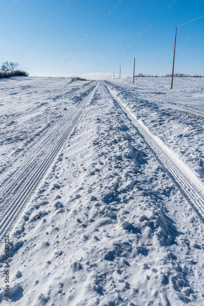 Vehicle tracks through deep snow on a rural road in Saskatchewan, Canada
