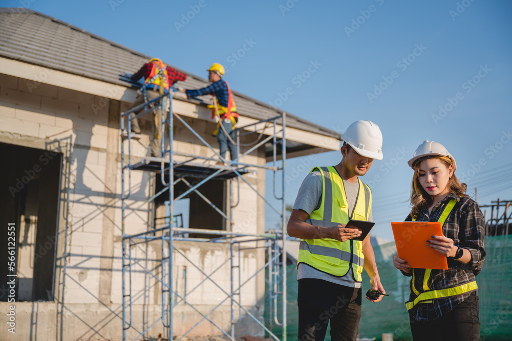 Asian male construction engineer talking to two Asian female architects a man using a tablet standing at a construction site to explain home design work Asian male construction engineer talking to two Asian female architects a man using a tablet standing at a construction site to explain home design work