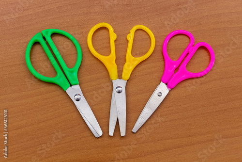 Multi-colored stationery scissors on the surface of the office table.
