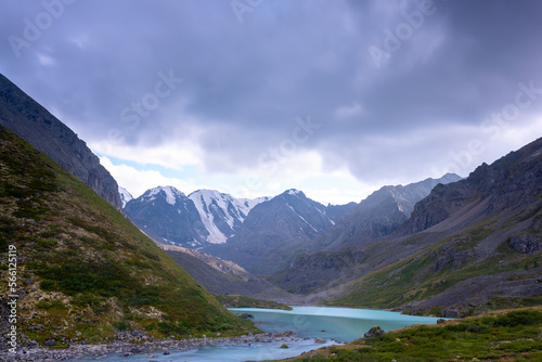 Mountain lake calm turquoise with clear water Karakabak in the Altai mountains with snow and glaciers under thick clouds. © Дмитрий Седаков