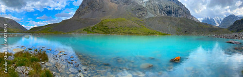 Panorama transparent turquoise water mountain lake Karakabak among stone rocks with a day in Altai in summer under a blue sky.
