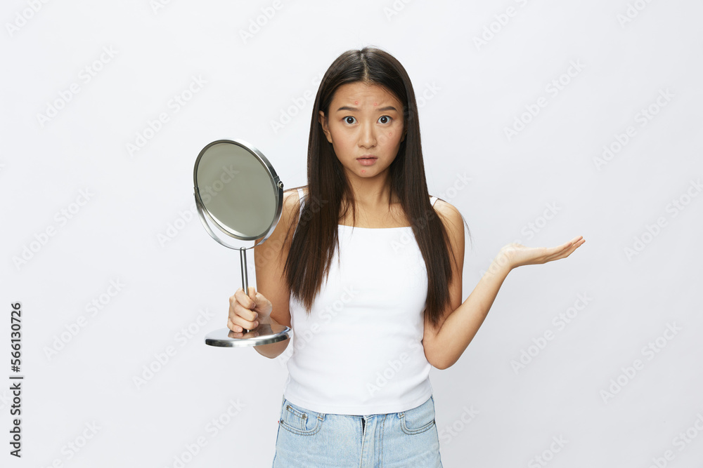 Asian woman with mirror in hand facial skin problems, acne and inflammation, red rash and allergies, chicken pox, sadness from rashes. Facial skin care concept for diseases and nerves Asian woman with mirror in hand facial skin problems, acne and inflammation, red rash and allergies, chicken pox, sadness from rashes. Facial skin care concept for diseases and nerves
