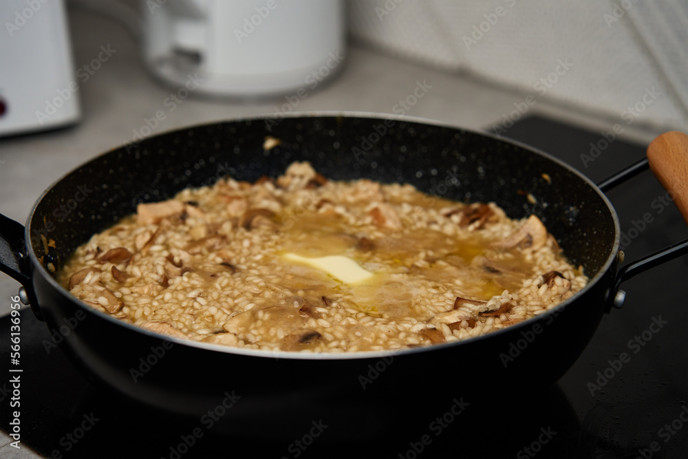 Process of cooking risotto. Arborio rice and piece of butter in frying pan in home kitchen. Italian cuisine dish Process of cooking risotto. Arborio rice and piece of butter in frying pan in home kitchen. Italian cuisine dish