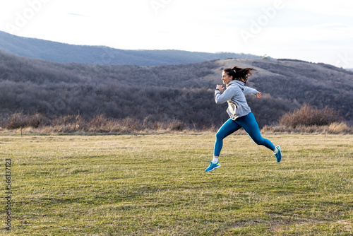 Jogger woman run in nature far away from urban city and exercise at the end of day in the middle of field