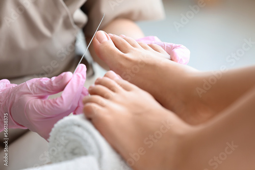 Young woman getting pedicure with file in beauty salon  closeup