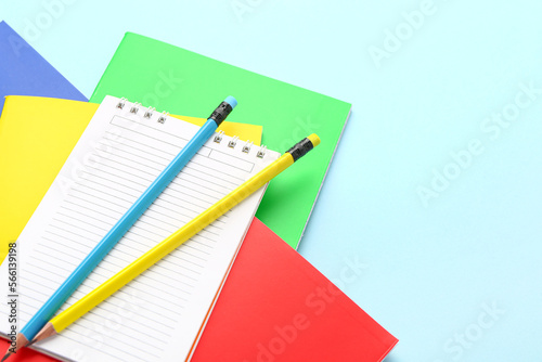 Different notebooks and pencils on color background, closeup