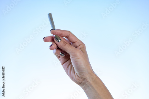Girl holding joint in the air with the sky in the background