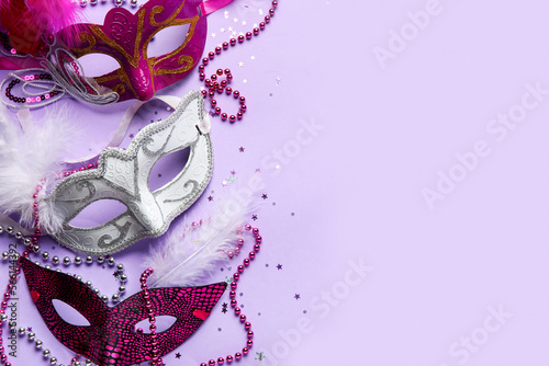 Carnival masks for Mardi Gras celebration with beads and confetti on lilac background