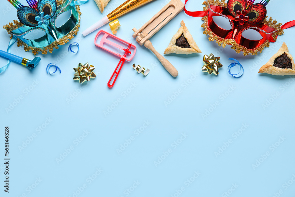 Hamantaschen cookies, carnival masks and rattles for Purim holiday on blue background