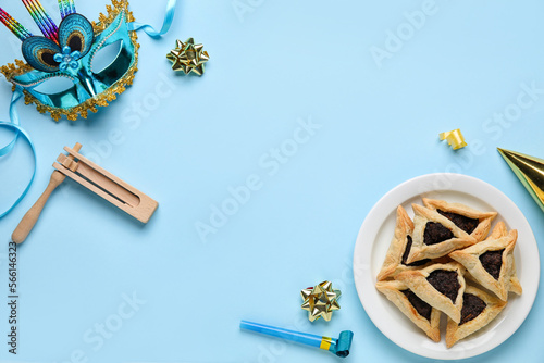 Frame made of Hamantaschen cookies, carnival mask and rattle for Purim holiday on blue background photo