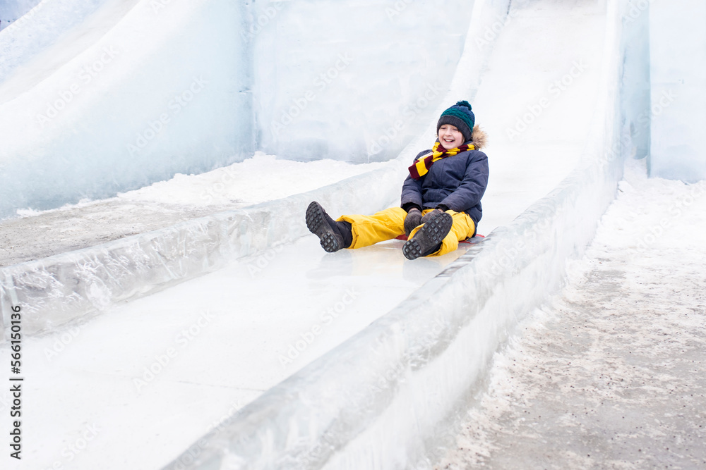 happy boy slides down an ice slide in winter outside happy boy slides down an ice slide in winter outside