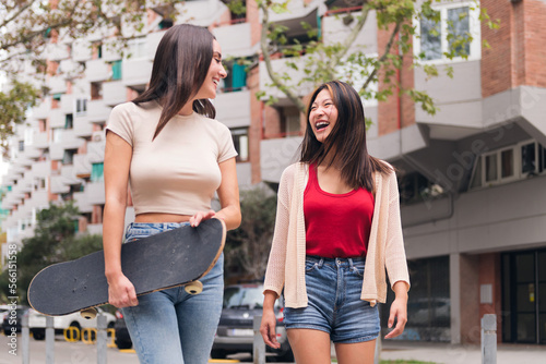 two young women friends laughing and walking happy through the city, concept of female friendship and teenager lifestyle © Raul Mellado