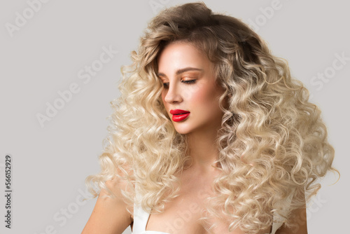 Portrait of a beautiful blonde woman with red lipstick on her lips. Curly blond long hair. Hairstyle