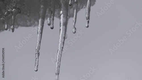 Close-up of water drops from icicles on drifting dark snow clouds. Time-lapse recording.