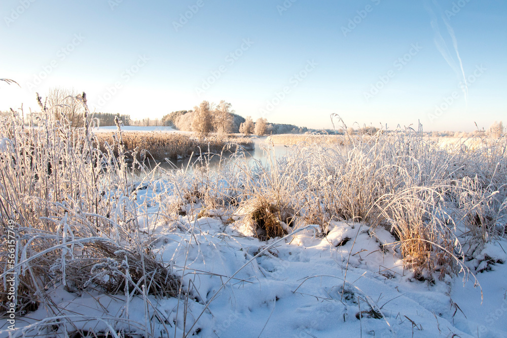 Beautiful landscape of nature in earky spring. All nature in hoarfrost. Dry grass on the beach river covered with snow. Beautiful view on river and her banks in dry grass.