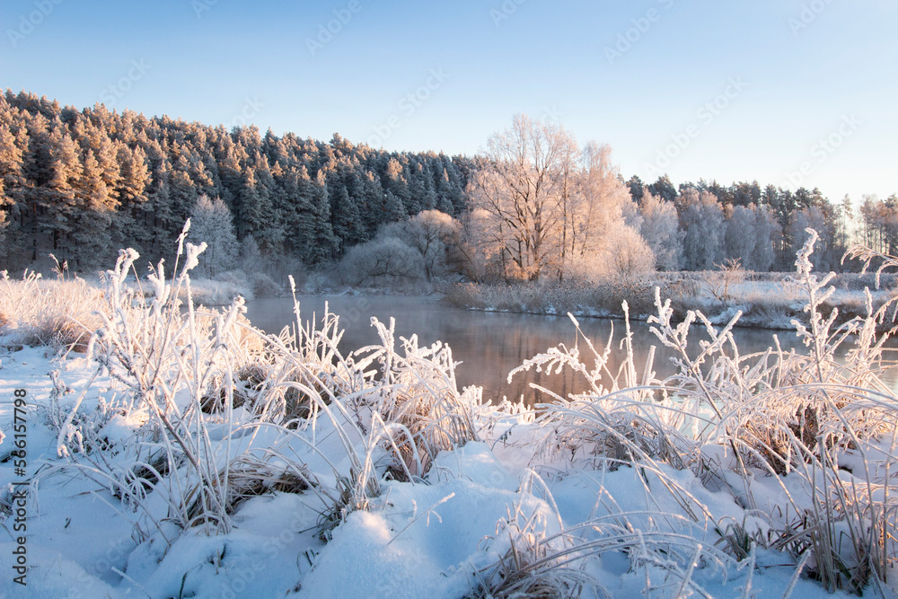 First month of spring, march. Beautiful landscape of nature in early frozen morning. All nature in hoarfrost. Sunbeams illuminate the edge of the forest. Over river are light mist.