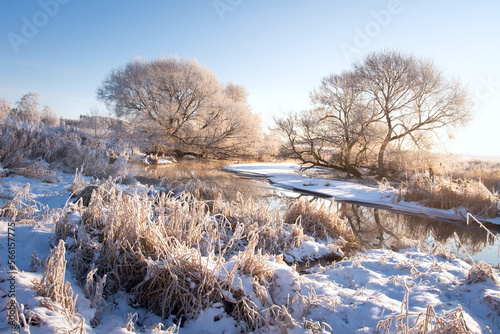 Obraz na płótnie Amazing landscape of the river bank and meadow near. Dry grass covered with snow on the beach river. All nature in hoarfrost. Over river are light mist.
w salonie