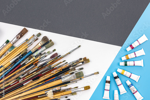 Brushes for drawing and paint on paper colored background, flat lay.