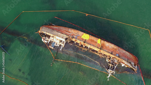Aerial top view of overturned broken rusty oil tanker ship in the shallow water. Drowned ship after the wreck.