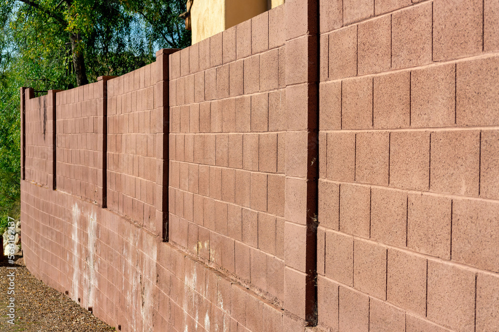 Red brick retaining wall in late afternoon sunlight with gravel floor and trees in background and stucco wall exterior Red brick retaining wall in late afternoon sunlight with gravel floor and trees in background and stucco wall exterior