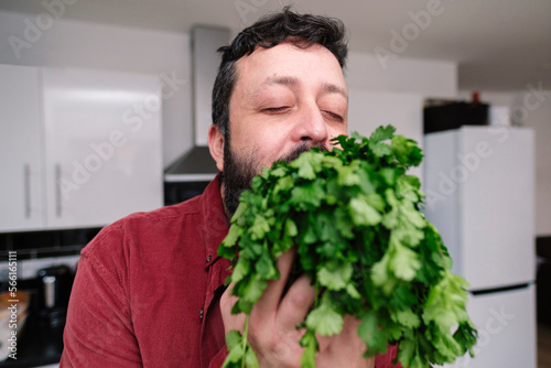 Mature man with eyes closed holding cilantro at home