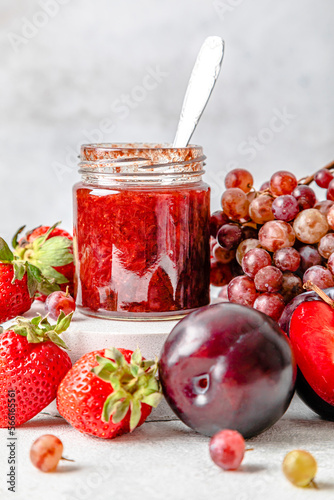 Homemade strawberry jam with various fruits kept on table photo