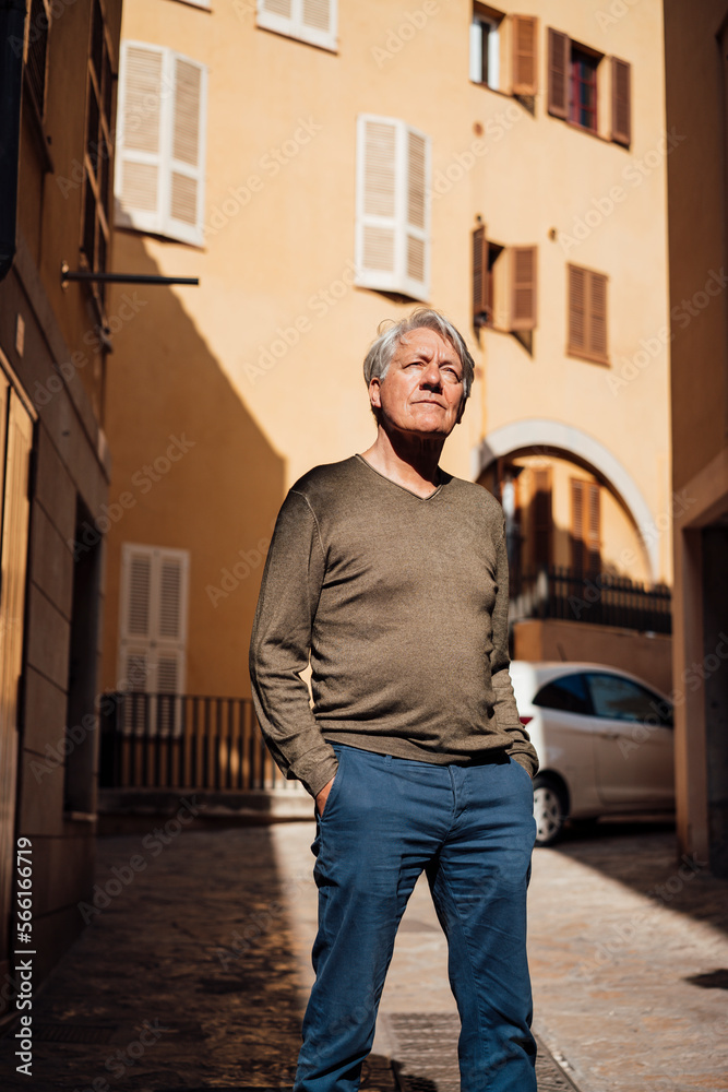 Senior man with hands in pockets standing in front of building Senior man with hands in pockets standing in front of building