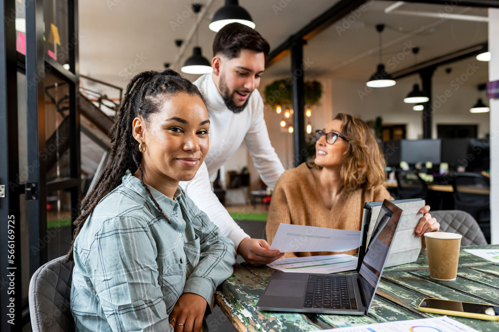 Smiling businesswoman with coworkers sitting in meeting room at office Smiling businesswoman with coworkers sitting in meeting room at office