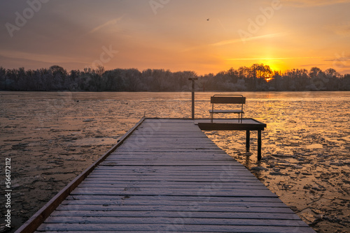 frosted pier over a frozen river during a beautiful sunrise