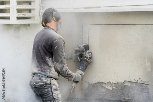 A man worker using a professional angle grinder to cut beton wall.