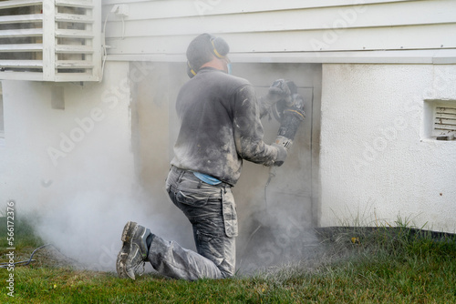 Adult man cutting beton hose wall.