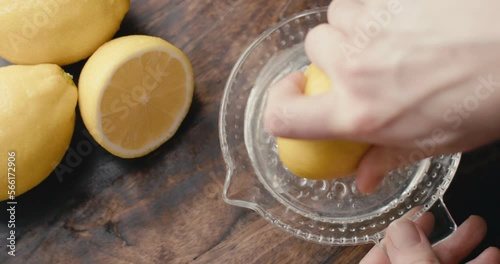 Hand squeezes fresh lemon juice on glass squeezer top down close up