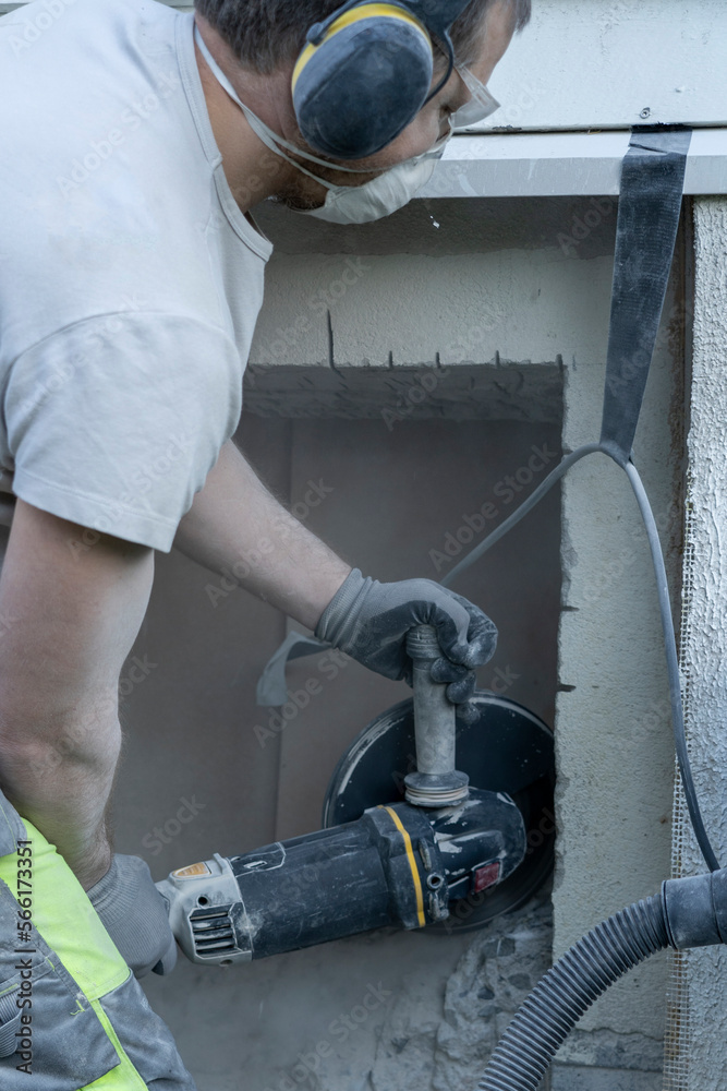 Adult man cutting beton hose wall.