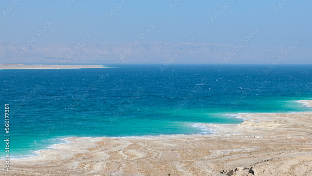Landscape view of the Dead Sea with patterned salt deposit coastline and turquoise water in Jordan Rift Valley, Middle East
