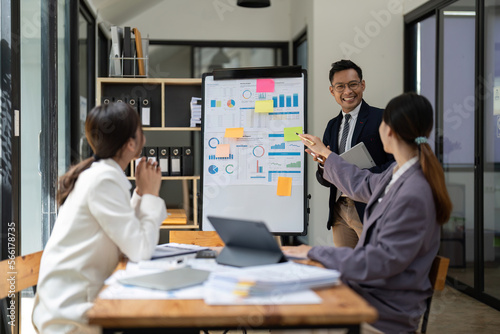 Business adviser explaining business plan strategy on flipchart to colleagues, male coach or adviser giving presentation at briefing, reporting about results or growing sales