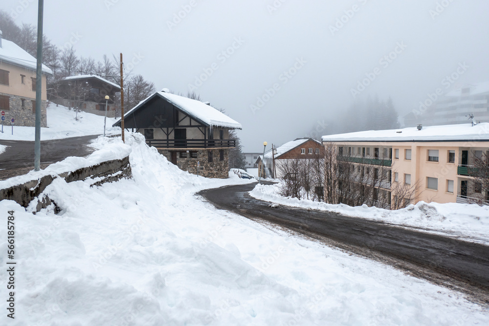 Estrada a meio de uma vila coberta por muita neve e nevoeiro num dia frio de inverno em Gourette, Pirenéus Atlânticos, França Estrada a meio de uma vila coberta por muita neve e nevoeiro num dia frio de inverno em Gourette, Pirenéus Atlânticos, França