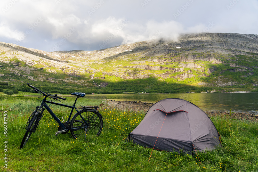 Bike with trekking tent next to a fjord in Norway with mountains and mist in the background