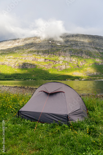 Trekking tent next to a fjord in Norway with mountains and mist in the background
