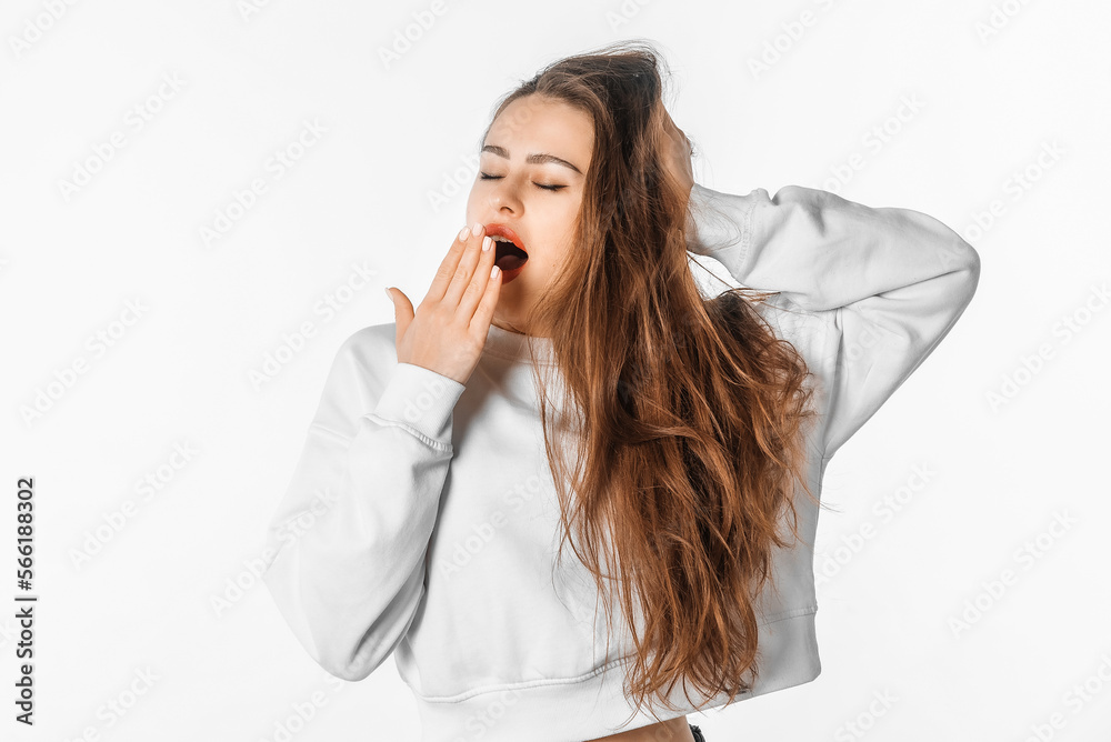 Sleepy young woman covering her mouth while yawning. Tired brunette female yawn from boredom, posing against white studio background Sleepy young woman covering her mouth while yawning. Tired brunette female yawn from boredom, posing against white studio background