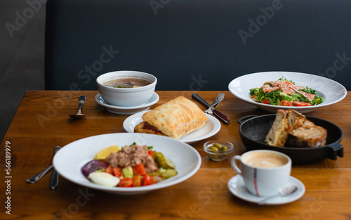 Full table of delicious and different dishes in cafe with cup of coffee in white dinnerware. (ID: 566189979)