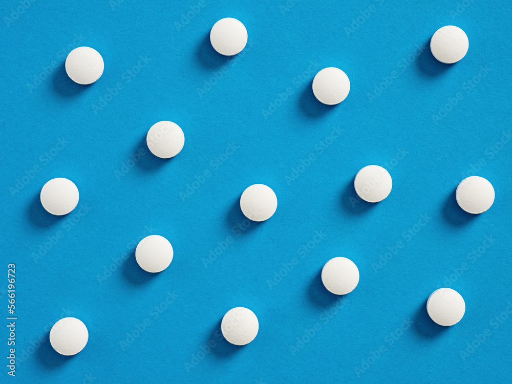 White round medical pills on blue background. Medical and pharmaceutical treatment concept. White round medical pills on blue background. Medical and pharmaceutical treatment concept.